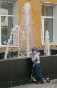 Ребенок на самокате у фонтана
